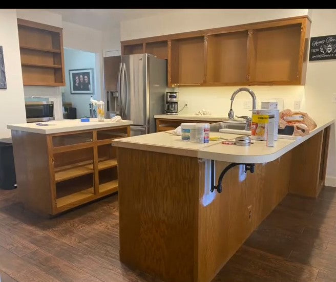 a kitchen mid renovation showcasing wood cabinets a bar to the right and an island in the center