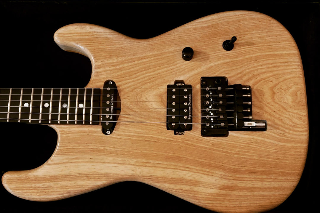 electric guitar in a light wood finish on a black background