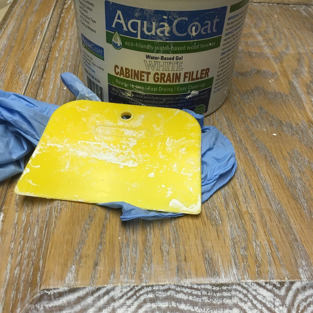 Aqua Coat Grain Filler sitting beside a pair of blue gloves and a yellow applicator