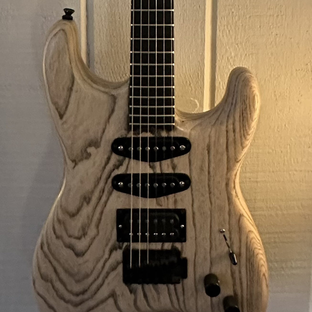 Guitar in light wood grain with prominent wood grain marks on the front