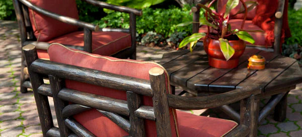 up close photo of an outdoor furniture set showcasing a dark wood table and chairs with red cushions