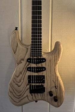 electric guitar in a light wood finish with heavy dark grains