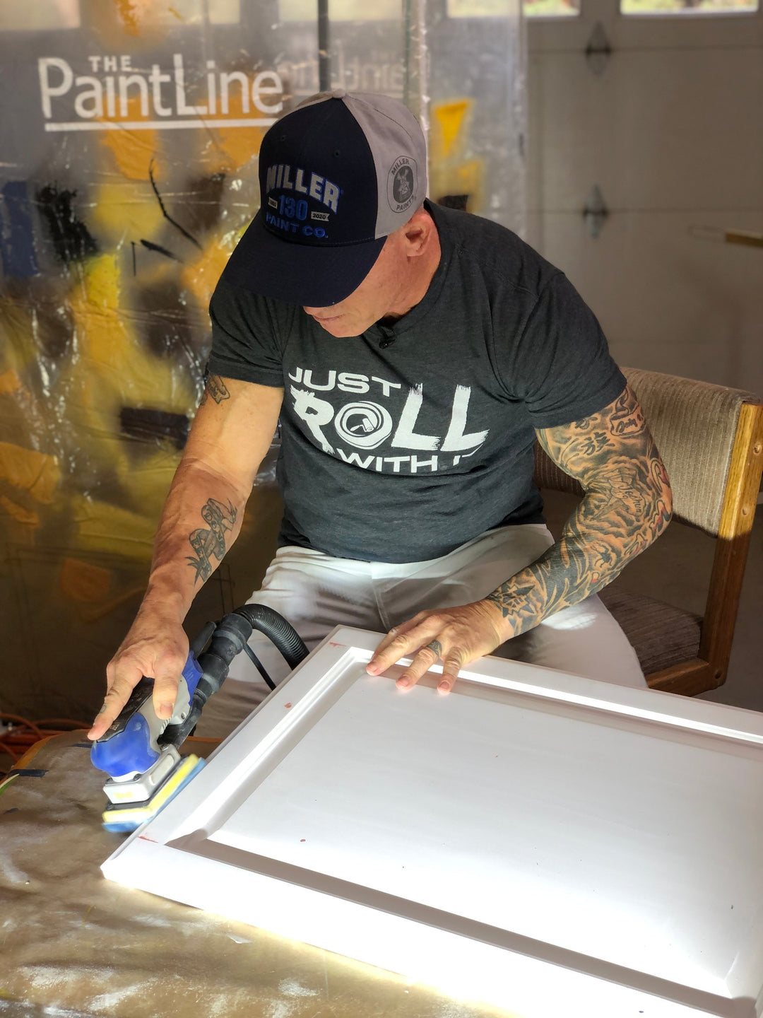 the idaho painter sanding a white cabinet with a hat on