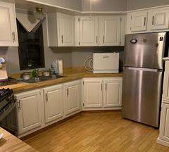 white kitchen cabinets with butcher block counter tops and stainless steel fridge
